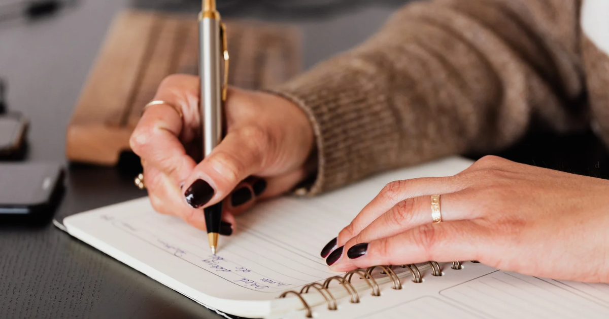 Therapist handwriting session notes in a spiral notebook